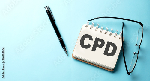 CPD text written on a notepad on the blue background photo
