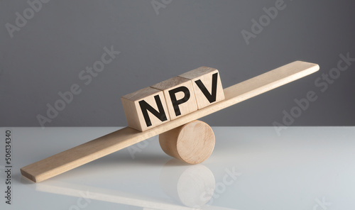 NPV on wooden cubes on a wooden balance , business concept © Iryna