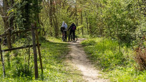 Young teenagers cycling on a grassy path, from behind, in the spring © GlobalMedia