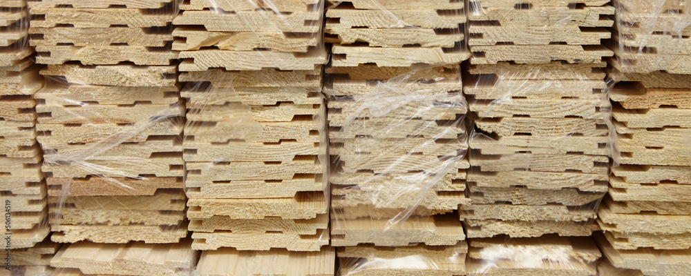 Pine wooden lining mouldings in plastic packaging closeup wide view. Production and storage of profiled boards