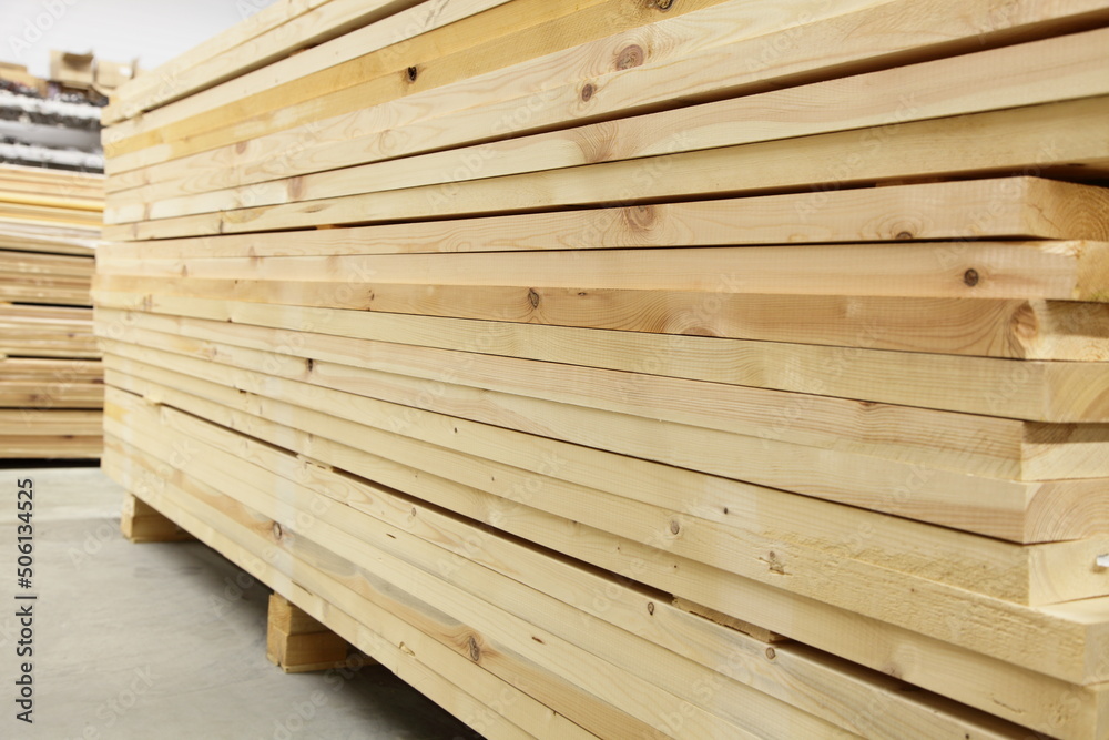 A lot planed wooden boards in horizontal stack in perspective. Carpentry plant warehouse. Building shop.