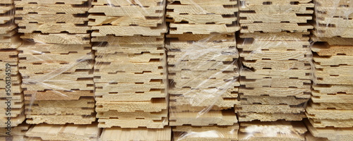 Obraz na płótnie Pine wooden lining mouldings in plastic packaging closeup wide view. Production and storage of profiled boards w salonie