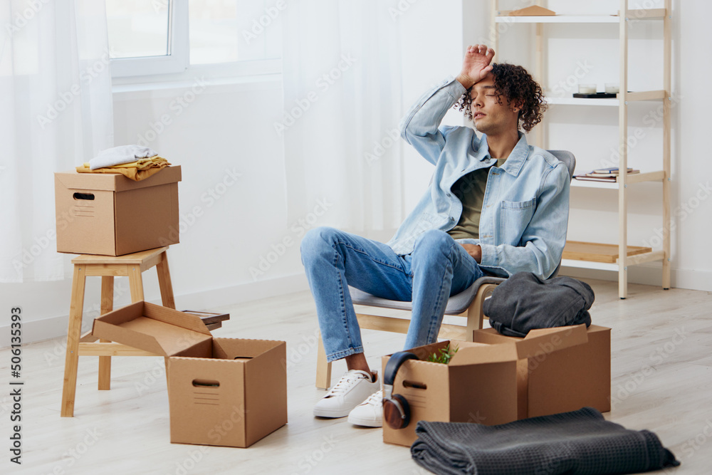 portrait of a man sitting on a chair unpacking with box in hand moving sorting things out portrait of a man sitting on a chair unpacking with box in hand moving sorting things out