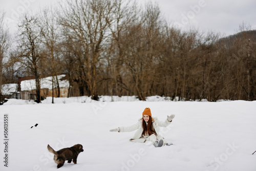 Fototapeta Naklejka Na Ścianę i Meble -  young woman in the snow playing with a dog fun friendship winter holidays