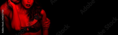 Fotografie, Obraz Sensual brunette woman in underwear with young lover in red ligh