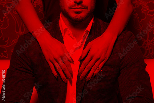 Sexy woman hands embrace rich man in red light photo