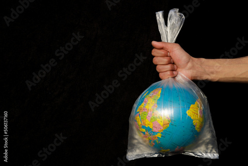 Earth wrapped up in plastic bag. Globe in a plastic bag. Concept of plastic pollution of the earth. World Environment Day concept. Copy space. Save Earth Concept on black background Selective focus.