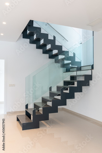 A modern staircase. Openwork stairs made of metal and marble, and glass balustrades.