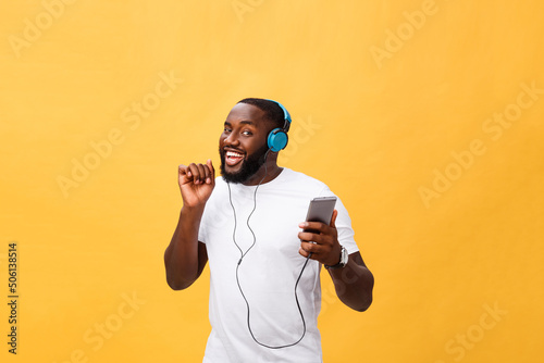 African American man with headphones listen and dance with music. Isolated on yellow background photo