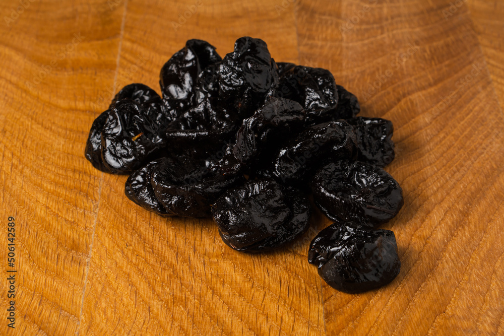 Dried dried prunes in a heap on a wooden board Dried dried prunes in a heap on a wooden board