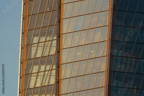 Reflection of sunset on the huge glass facade of skyscraper  wall of orange color