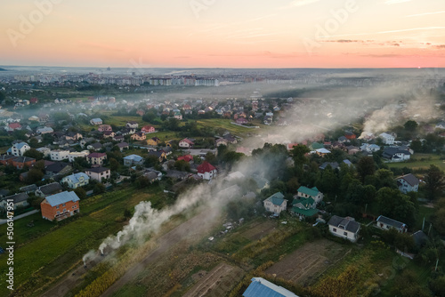 Aerial view of agricultural waste bonfires from dry grass and straw stubble burning with thick smoke polluting air during dry season on farmlands © bilanol