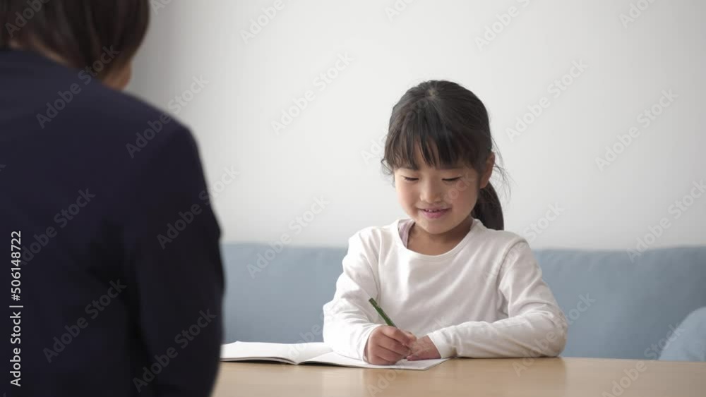 家で勉強をする女の子と見守るお母さん 家で勉強をする女の子と見守るお母さん