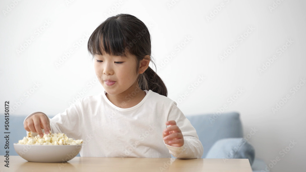 リビングでポップコーンを食べる女の子 リビングでポップコーンを食べる女の子