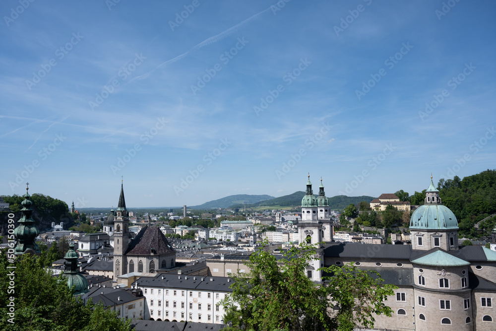 View of the old town of Salzburg, Austria, including the cathedral (right) and Franciscan Church (left), on a sunny day with a blue sky