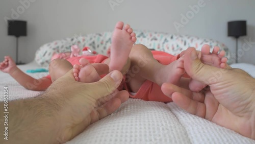 Barefoot taby twins and their feet in hands of father, newborns and parent, close up FPV photo