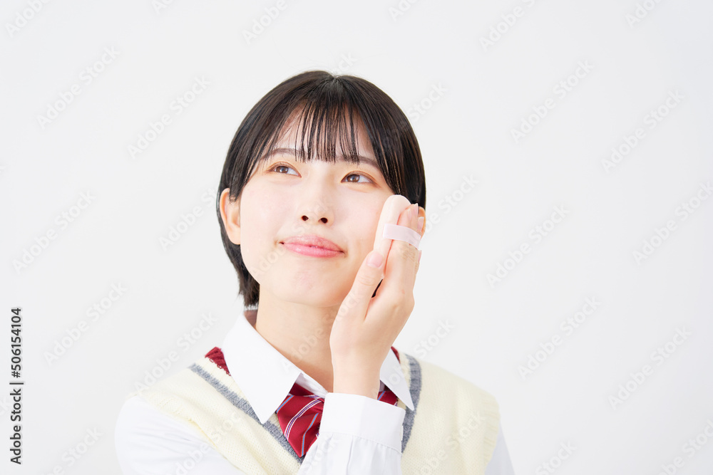 白背景でパフを使ってメイクする女子高生 白背景でパフを使ってメイクする女子高生