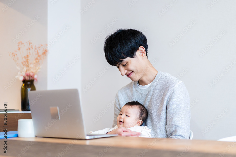赤ちゃんをお世話しながら在宅勤務をするパパ 赤ちゃんをお世話しながら在宅勤務をするパパ