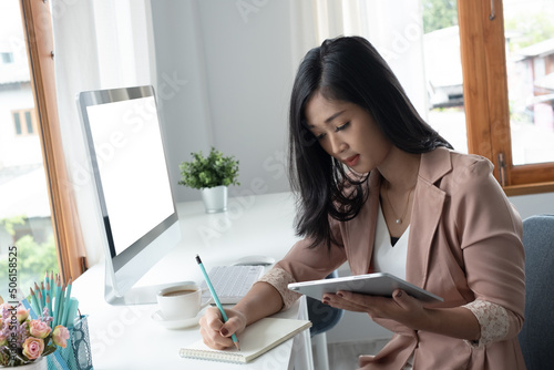 Business woman or accountant hand using calculator, working on taplet and laptop computer with documentary data graph paper on the table at modern home office. Online marketing concept.. photo