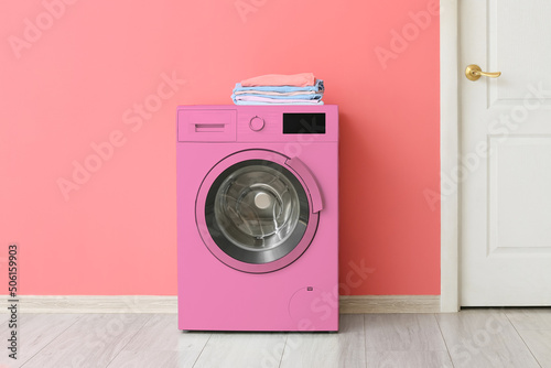 Pink washing machine near color wall