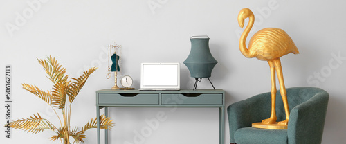 Photography Interior of room with comfortable workplace, armchair, golden flamingo and tropi