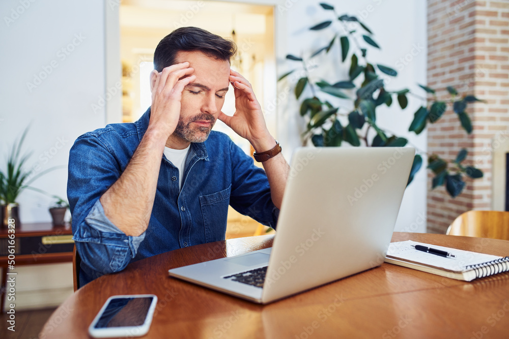 Thoughtful worried man working from home sitting at a table with closed eyes Thoughtful worried man working from home sitting at a table with closed eyes