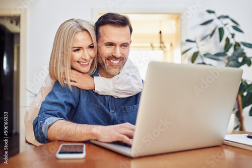 Happy middle aged couple doing online shopping on laptop