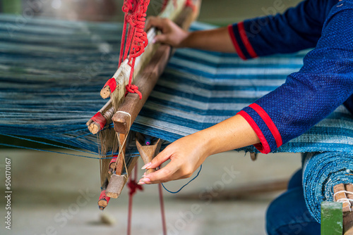 Craftsmen of Thai indigo cotton. Hand of young woman weaving silk in traditional way at manual loom. photo