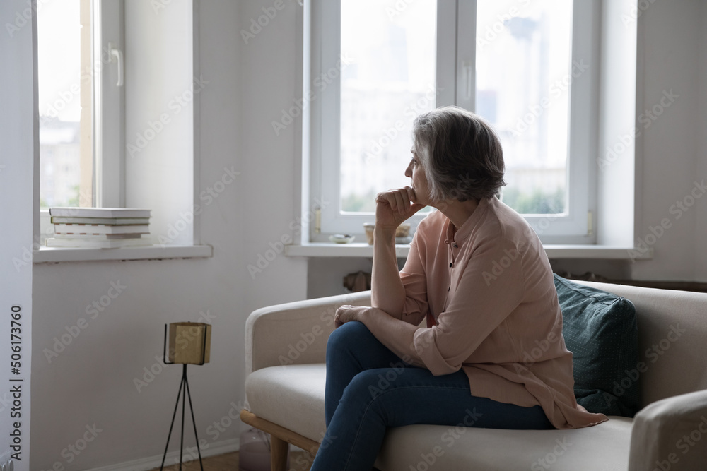 Sad lonely mature grey haired lady looking at window away, thinking over health problems, loneliness, bad news, loss, suffering from apathy, mourning depression. Frustrated middle aged woman at home Sad lonely mature grey haired lady looking at window away, thinking over health problems, loneliness, bad news, loss, suffering from apathy, mourning depression. Frustrated middle aged woman at home