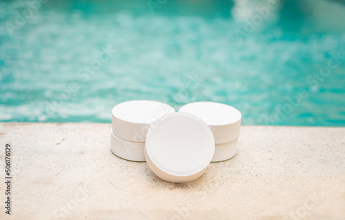 Close-up of some chlorine tablets for cleaning on the edge of a swimming pool, chlorine tablets to clean swimming pools, concept of chlorine tablets to disinfect swimming pools photo