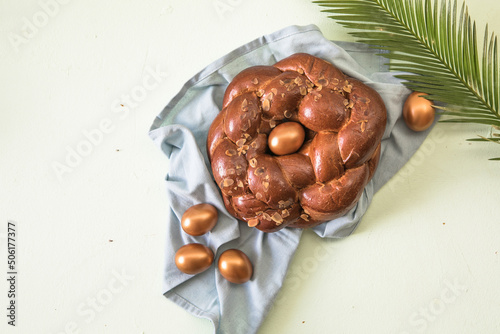 Tsoureki traditional baked Greek Easter sweet bread, garnished with slivered almonds and decorated with a boiled red dyed egg in the middle photo