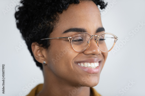 Close up cropped view face of attractive African woman in glasses having wide toothy smile look aside pose on white studio background. Eyewear, lenses store ad, happy young 20s female portrait concept