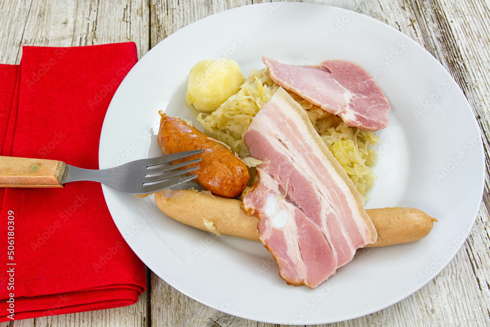 sauerkraut garnished with bacon sausages and a potato on a plate sauerkraut garnished with bacon sausages and a potato on a plate