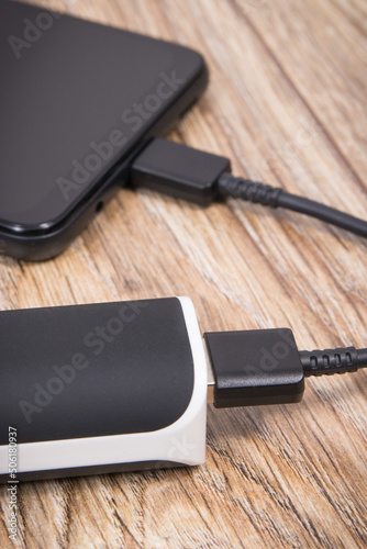 External powerbank using to charge empty battery of black smartphone