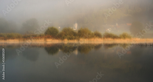 Autumn mist by the lake with beautiful calm reflections.