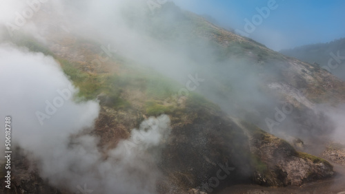 The hillside is shrouded in thick steam from an erupting geyser. Poor visibility due to haze. Kamchatka. Valley of Geysers