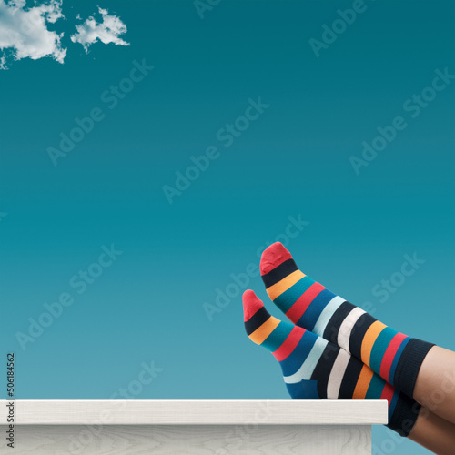 Creative person with multicolor sock relaxing with feet up