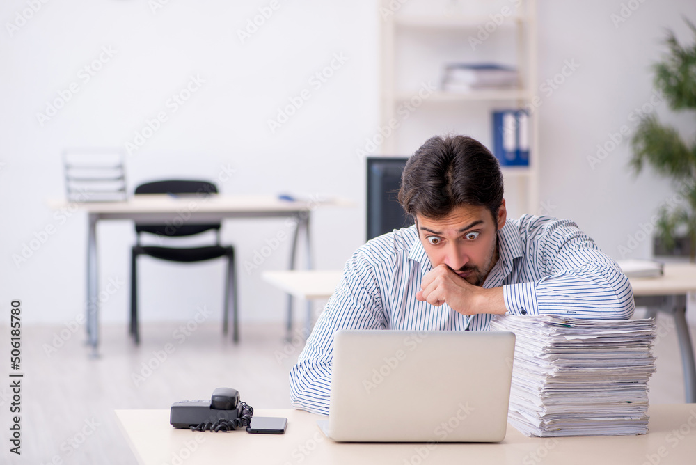 Young male employee and too much work in the office Young male employee and too much work in the office