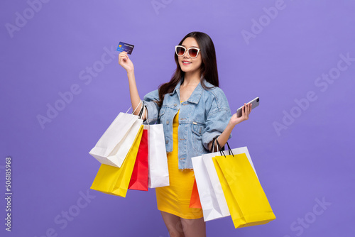 Canvas Print Beautiful smiling young Asian woman carrying colorful bags and showing credit ca