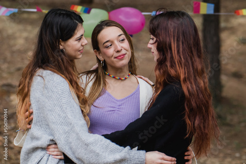 Young lesbian women in polyamory relationship. Diversity flags in background photo