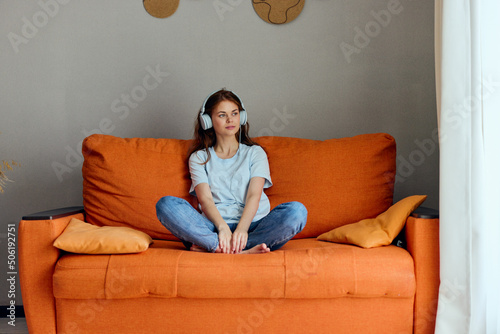 woman on the orange sofa listening to music with headphones apartments