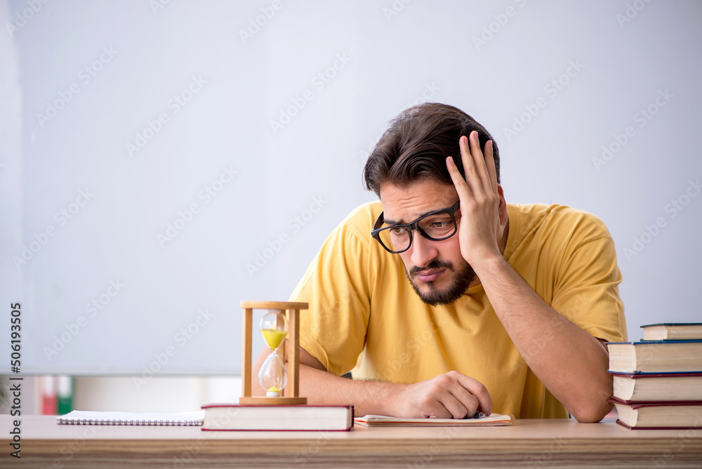 Young male student in time management concept Young male student in time management concept