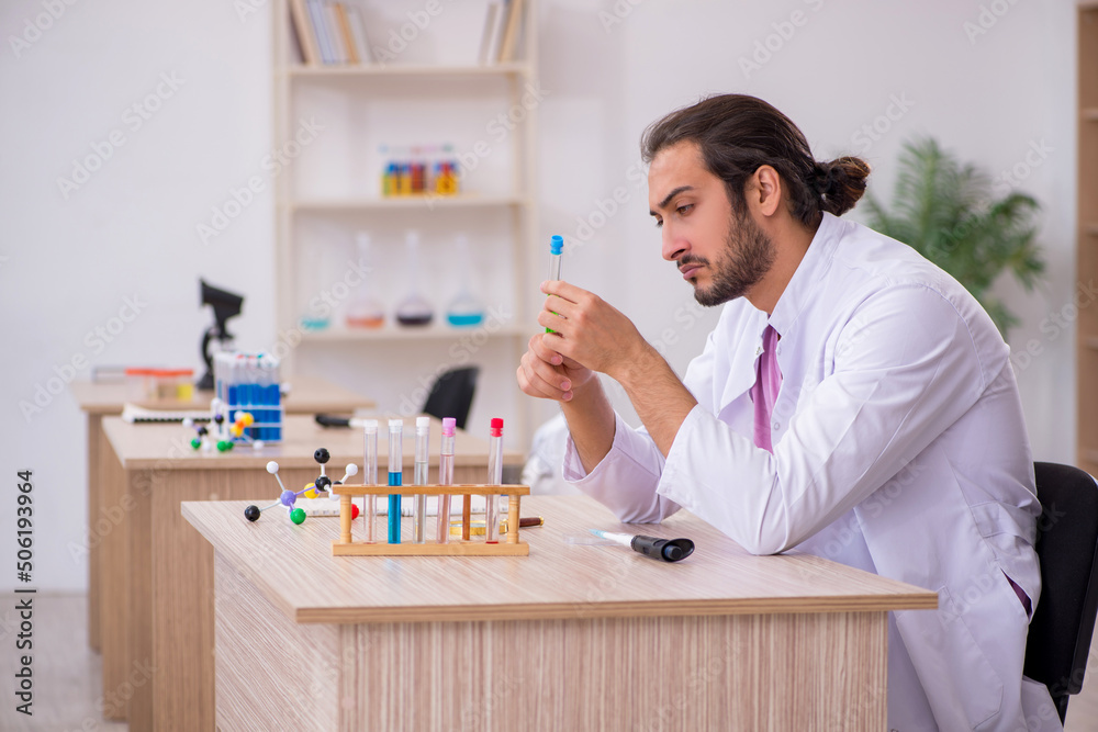 Young male chemist sitting at the desk in the classroom Young male chemist sitting at the desk in the classroom
