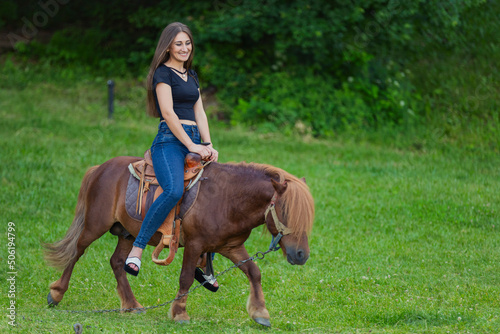 girl riding a pony on a green lawn