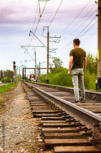 Man standing on train tracks On the Sunset. red light on coming train, selective focus