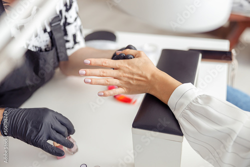 Manicure master doing nail care for client in work studio