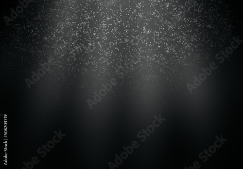 Dust particles in the light rays on a black background.