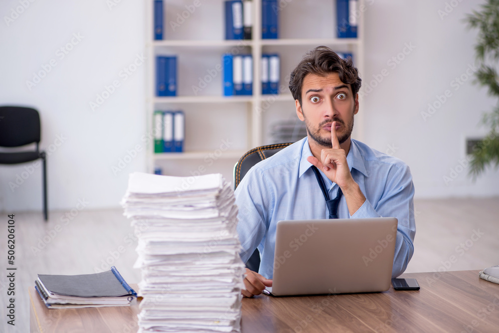 Young male employee and too much work in the office Young male employee and too much work in the office