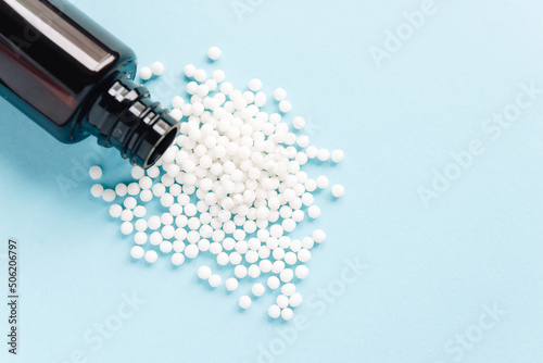 
Homeopathic pills and brown plastic bottle on a blue background. homeopathic medicine
