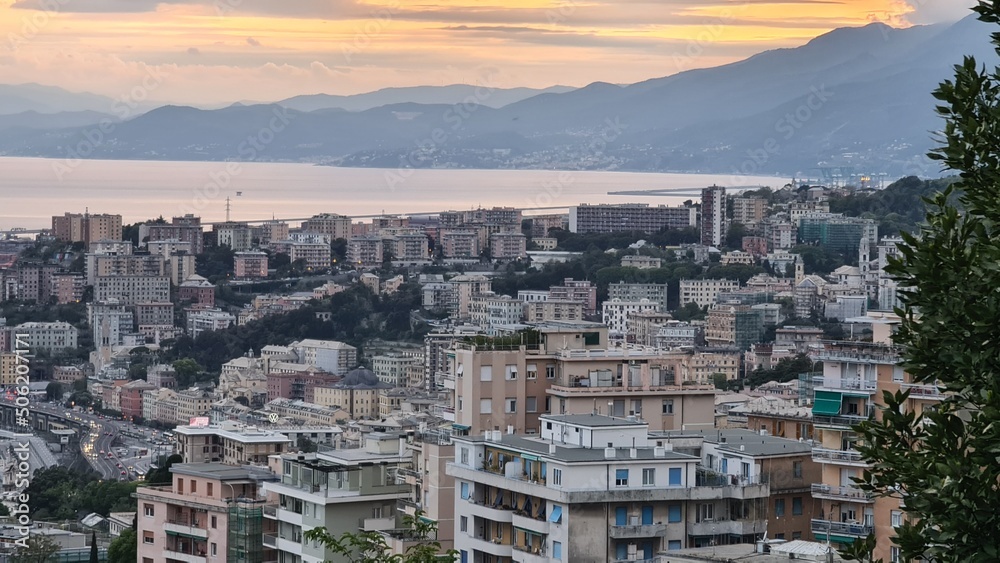 Genova, Italy - May 07, 2022: Panoramic  view from the sea to the old town, and the port with beautiful sunset. Genoa bay, harbor, yacht at the pier.tourist destinations.